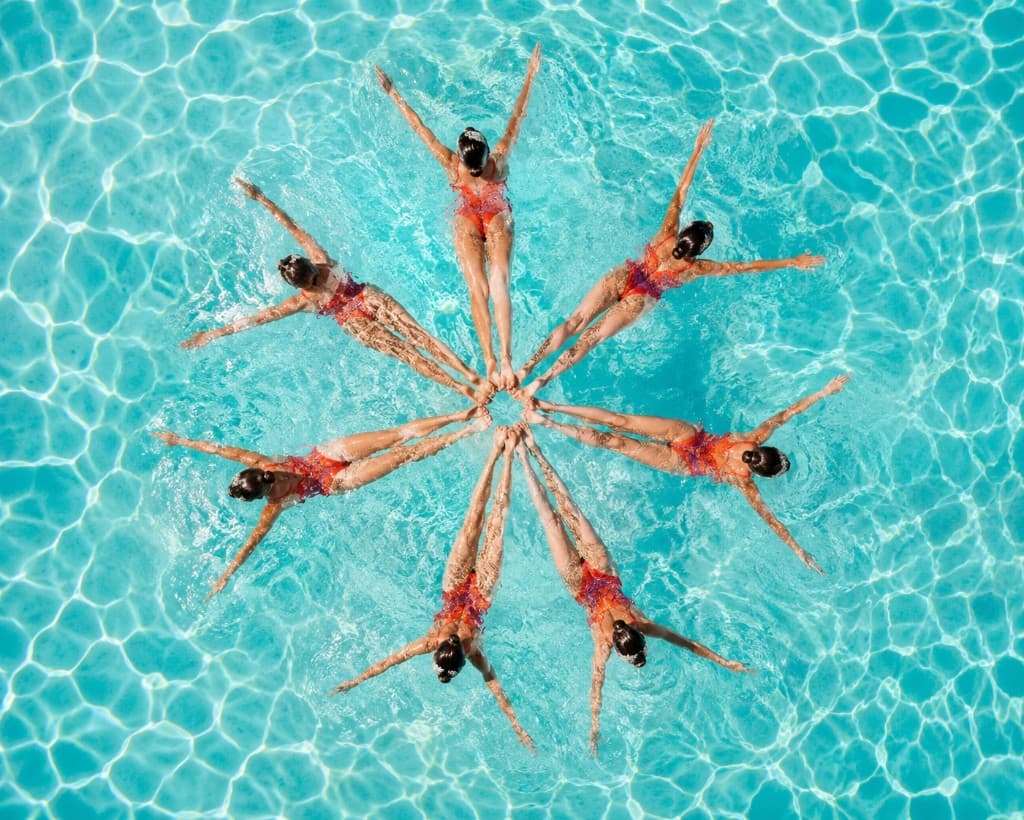 Equipo de natación sincronizada formando un círculo en el agua